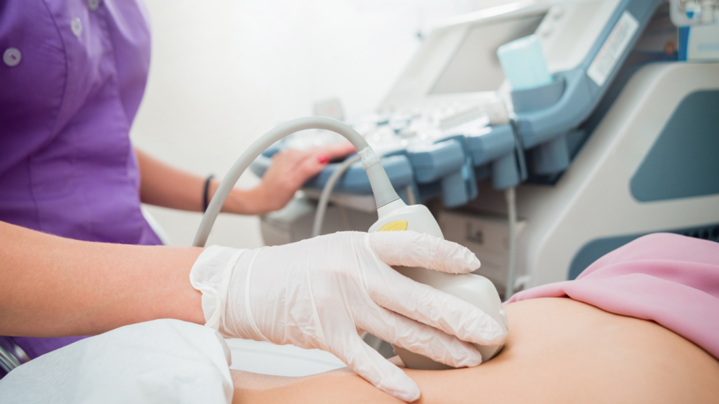 Closeup image of ultrasound technician performing an ultrasound on woman's belly