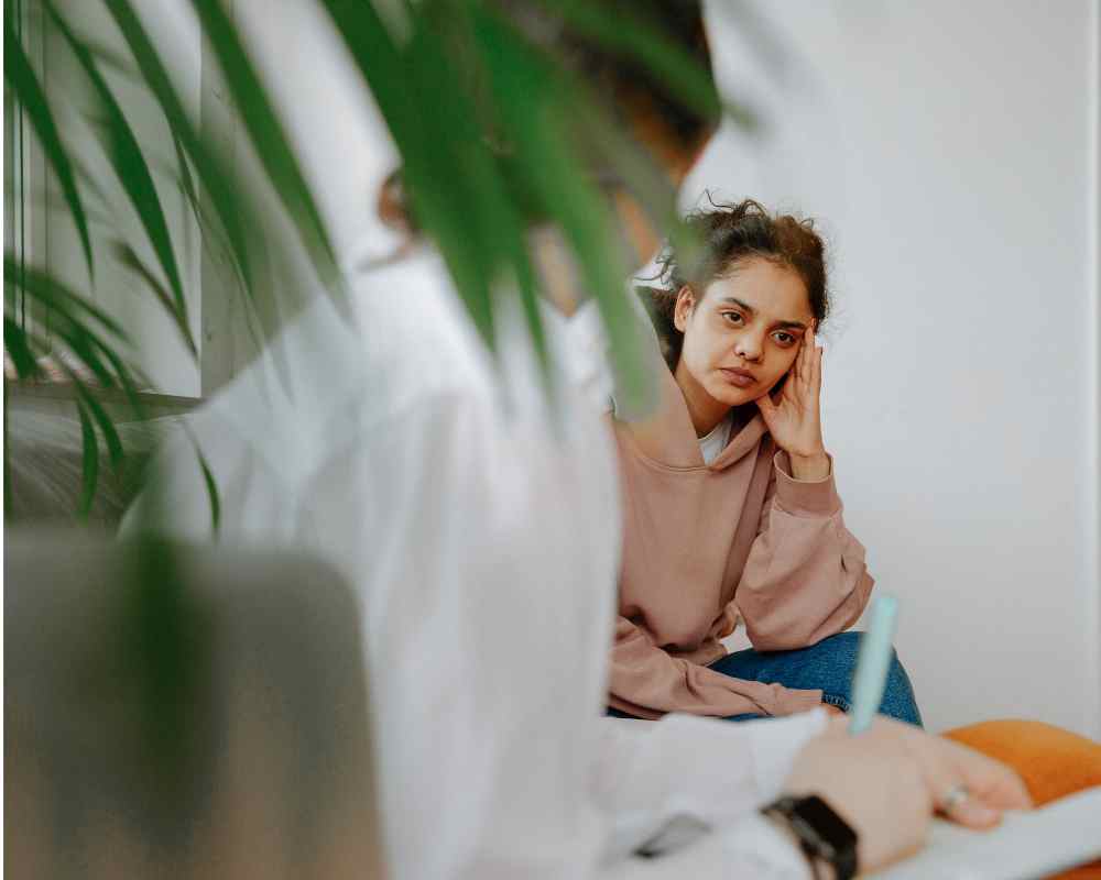 A view of a girl sitting with a counselor or doctor